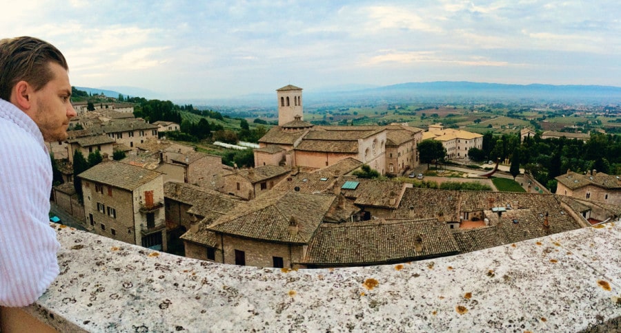 giotto hotel, Assisi, Italy, view from the balcony over the old town buildings and land far away, man in a bathrobe looking out