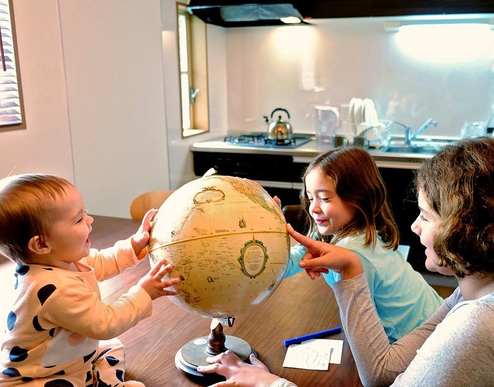Kids pointing to a world globe, in the kitchen, hotels
