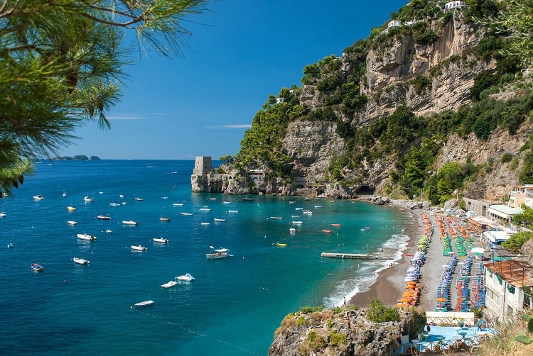 Fornillo Beach Positano Amalfi Coast, view of the buildings, beach umbrellas, boats anchored in the water, rocky cliffs