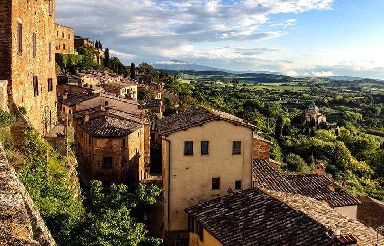 best-towns-in-tuscany-montepulciano, Italy, sunset view of the yellow buildings on the side of the hill, green lands in the distance