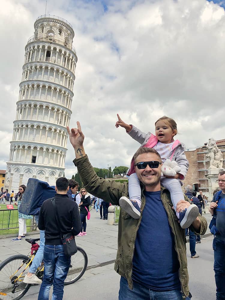 best towns to visit in tuscany - Pisa with kids, man with daughter on his shoulders pointing to the tower of Pisa, Italy