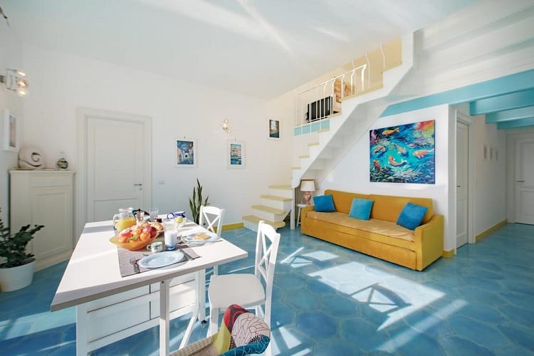 corricella-apartment in Procida in Italy, lounge and dining room, staircase to upstairs, blue floors