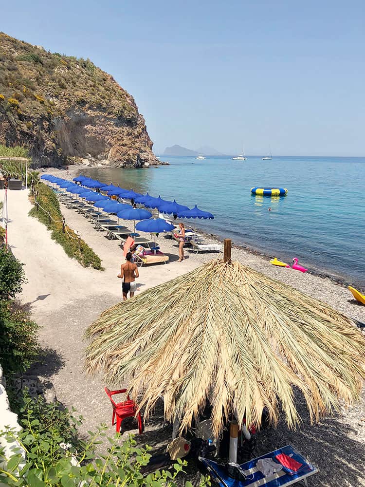 White Beach Lipari Island, Italy, straw and blue umbrellas lining the beach, sun loungers, beach