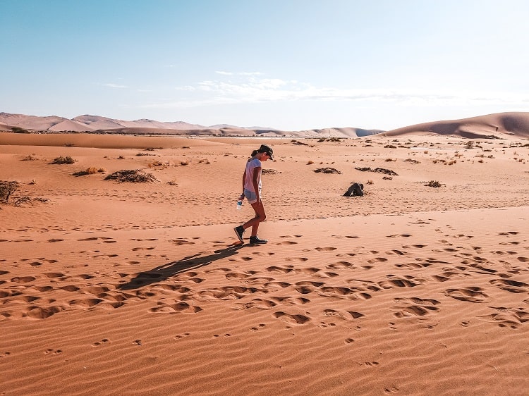 Namibia desert with Kids, young teenager girl walking in the desert, hat on, bottle of water in hand